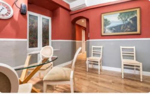 Sala dorata dello Yaki Domo B&B a Cagliari con pareti rosse, sedie bianche, pavimento in legno e zona pranzo