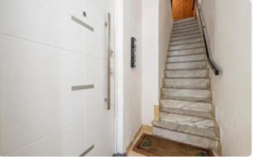 Scala ascendente nella camera Yaki Domo Gold del BnB di Cagliari, con pareti bianche e ringhiera in legno