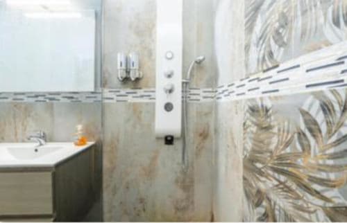 Bagno moderno nella camera Yaki Domo Silver a Cagliari con doccia piastrellata, lavandino e piastrelle botaniche decorative