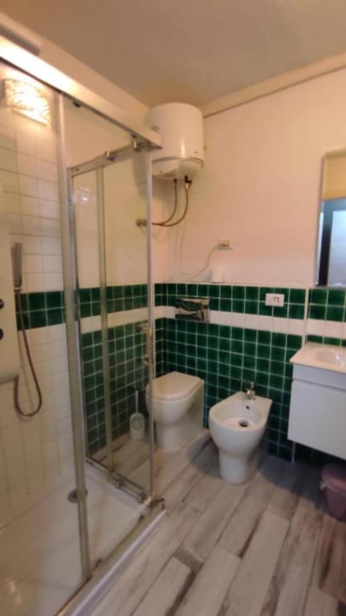 Bagno moderno della Yaki Domo B&B a Cagliari con parete di piastrelle verdi, doccia, WC, bidet e lavabo