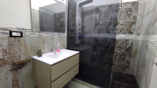 Bagno moderno nella camera Yaki Domo Silver, Cagliari. Vanity bianco, box doccia nero, piastrelle decorative.