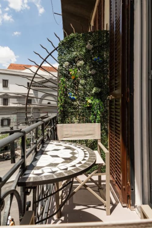 Balcone di Darna Rooms B&B a Napoli con muro ricoperto di edera, tavolo rotondo e vista sulla città