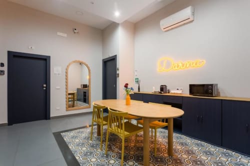 Darna Rooms Napoli - Camera Matrimoniale Deluxe con area dining, tavolo in legno, sedie gialle e insegna neon
