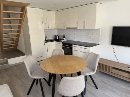 Appartement moderne ouvert à Zogbi Hospitality, Aubonne avec salle à manger, table ronde en bois, cuisine blanche