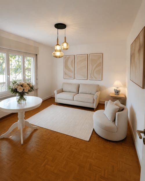 Séjour moderne à Lausanne avec canapé beige, table ronde, luminaires suspendus et vue montagne - Zogbi Hospitality.