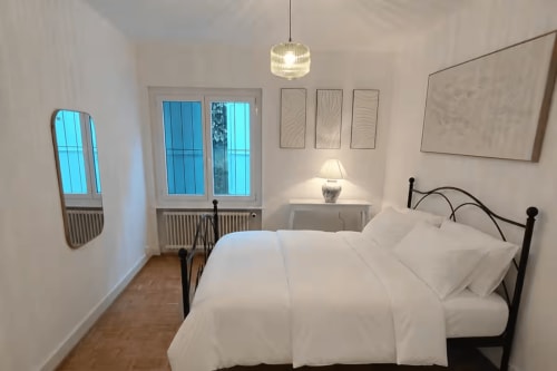 Chambre moderne à Zogbi Hospitality Lausanne avec literie blanche, structure de lit en métal noir, luminaire suspendu, miroir et vue montagne