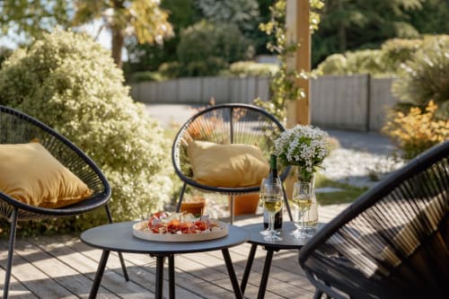 Outdoor patio seating at Manoir de la Nogrie with wine, appetizers, and flowering garden views