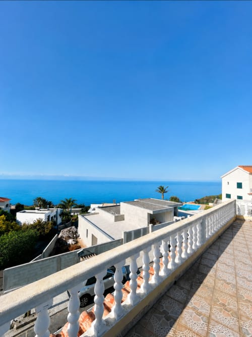 Villa Atlantic Escape em Funchal com varanda com vista para o mar, arquitetura mediterrânea branca, palmeiras e horizonte oceano azul.