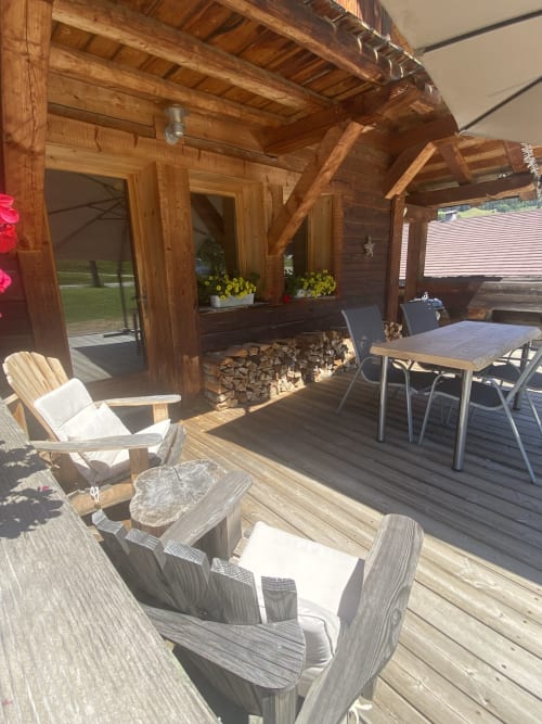 Terrasse en bois avec fauteuils Adirondack, table de salle à manger et vue sur les montagnes à La Ferme des Georgières