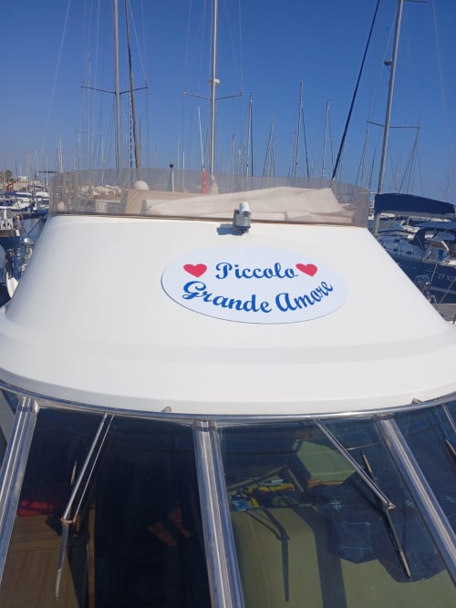 Yacht 'Piccolo Grande Amore' ormeggiato nella marina di Lampedusa con velieri sullo sfondo