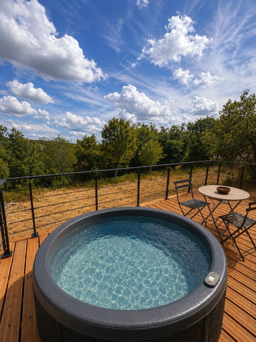 Baignoire privée sur terrasse en bois avec vue sur la forêt au Gîte l'Harmonie du Causse