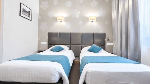 Deux lits jumeaux avec accents bleus dans une chambre moderne de l'Hôtel d'Orléans, Orléans France