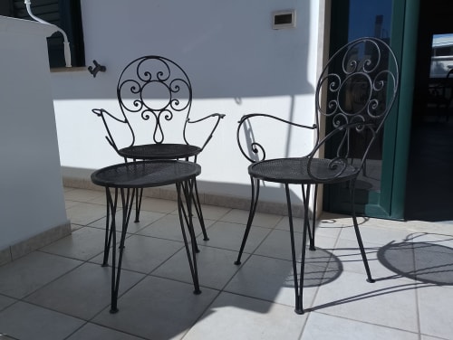Due eleganti sedie in ferro battuto con ornamenti decorativi sulla terrazza piastrellata di Casa Alba, Torre Lapillo