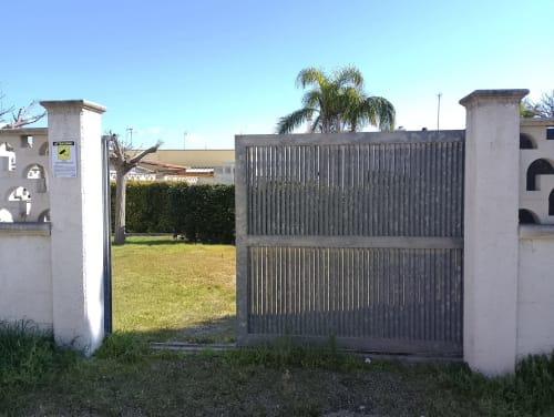Ingresso Villa Casa Alba con cancello in metallo e pilastri in pietra bianca, vista giardino proprietà Torre Lapillo
