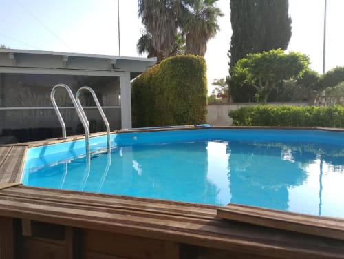 Piscina privata con acque cristalline della villa Casa Alba a Torre Lapillo, con scaletta in metallo, terrazza in legno e siepi curate