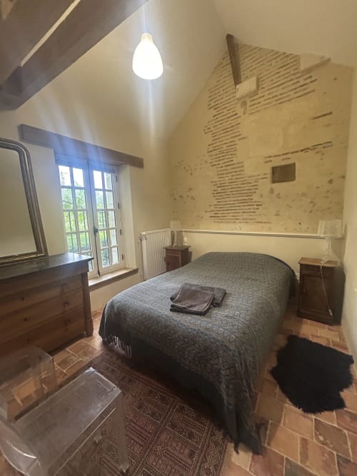 Chambre spacieuse au cottage Cour Du Liège avec lit queen-size, mobilier en bois et vue sur le jardin par portes-fenêtres