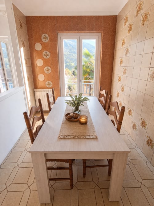 Sala da pranzo di Villaggio Lago Dorato con tavolo in legno chiaro, vista sulle montagne da porte-finestre e muri in cotto.