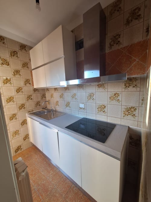 Cucina moderna con fornello, lavello e cabineteria bianca nell'Appartamento Agata a Villaggio Lago Dorato, Carlazzo