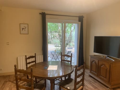 Salle à manger avec table en bois et chaises, TV écran plat, portes donnant sur le jardin, Appartement Hôtel De La Bonnheur, Bracieux France