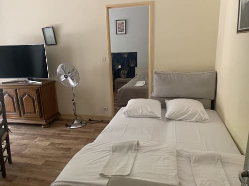 Chambre de l'appartement Hôtel De La Bonnheure avec lit, TV, ventilateur et miroir à l'entrée à Bracieux