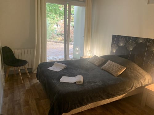 Chambre moderne de l'Hôtel De La Bonnheure avec vue sur jardin, literie foncée, tête de lit décorée et accès au jardin