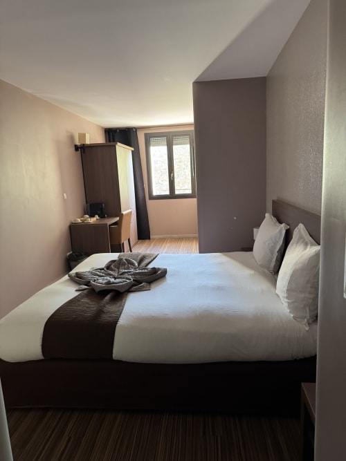 Modern double bedroom at Hôtel de la Bourse with white bedding, dark accents, desk, and city view balcony