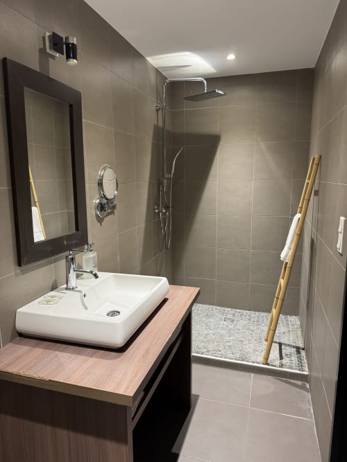 Modern bathroom in Hôtel de la Bourse, Bagnols-sur-Cèze with vessel sink, walk-in shower, and heated towel rack