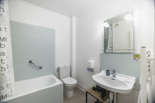 Salle de bain moderne à l'Hôtel De La Bonnheure avec lavabo, toilettes et baignoire avec cabine de douche en verre