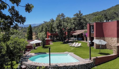 Piscina turquesa y exuberantes jardines en El Escondite De Pedro Malillo, un boutique hotel rústico de ladrillo rojo en Candeleda, España