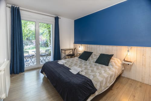 Chambre double moderne à l'Hôtel De La Bonnheur à Bracieux avec mur d'accent bleu, boiseries, vue sur le jardin