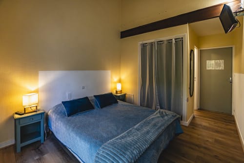 Chambre double moderne à l'Hôtel De La Bonnheure à Bracieux avec literie bleue, murs jaunes et vue sur le jardin