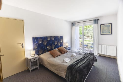 Chambre lumineuse à l'Hôtel De La Bonnheure, vue sur le jardin, tête de lit bleue à motifs et équipements modernes
