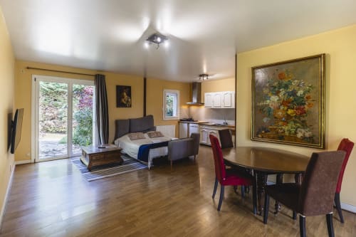 Spacieux appartement vue jardin à l'Hôtel De La Bonnheur à Bracieux avec murs jaunes, table à manger, lit et kitchenette.