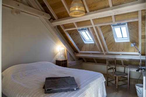 Chambre lumineuse sous les toits à la Cour Du Liège avec puits de lumière, poutres apparentes, literie blanche et plafond en bois à Baugé-en-Anjou