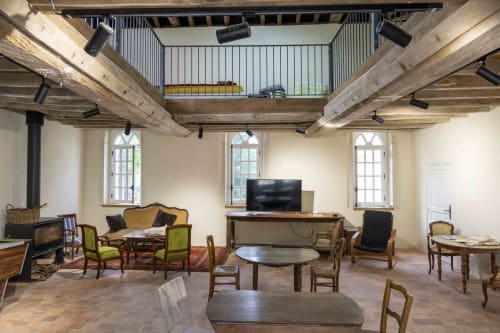 Spacieux hall de réception à Cour Du Liège avec poutres apparentes, mobilier rustique, cheminée et TV à Baugé-en-Anjou