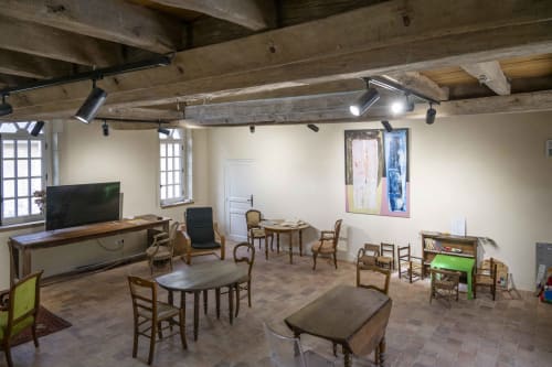 Spacieuse salle de réception à la Cour Du Liège à Baugé-en-Anjou avec poutres rustiques, coins lounge, télévision et mobilier d'époque
