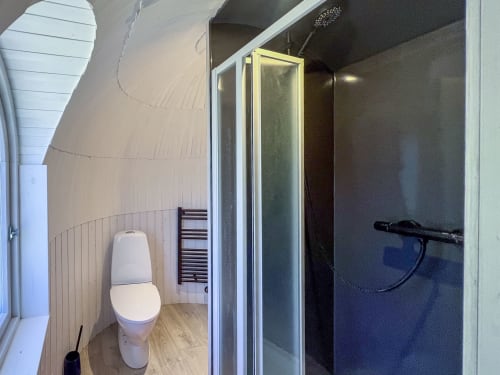 Salle de bains moderne de la tiny house Cour Du Liège avec toilettes, cabine de douche et murs blancs