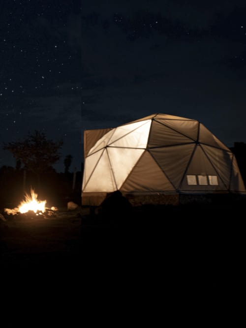 Domo geodésico iluminado en Mars Glam Camp de Aguascalientes con fogata nocturna bajo cielo estrellado
