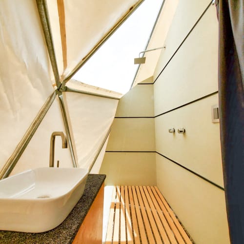 Baño moderno con domos en Mars Glam Camp: lavamanos de cerámica, piso de madera y tragaluz en Aguascalientes