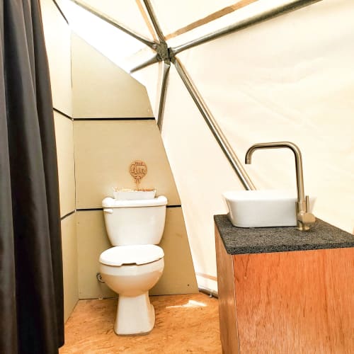 Baño de domo glamping con inodoro blanco, lavamanos y grifo cromado en Mars Glam Camp, Aguascalientes, México