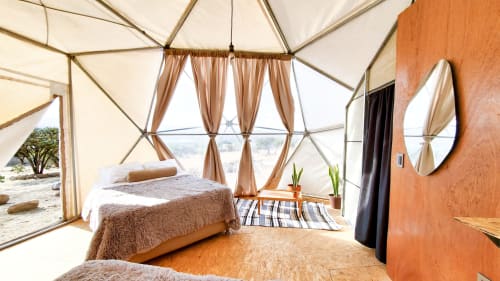 Dormitorio glamping en domo del Mars Glam Camp en Aguascalientes con cama, ventanales curvos y vista al lago