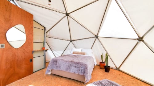 Dormitorio en domo geodésico climatizado en Mars Glam Camp, Aguascalientes, con ropa de cama púrpura, espejo redondo y cactus