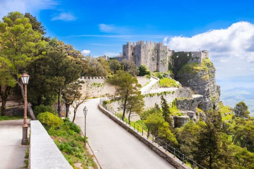 Rovine di castello medievale su scogliera rocciosa vicino Valderice, Sicilia con sentiero in pietra e vegetazione lussureggiante