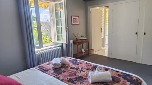 Bright double bedroom at Le Moulin de Bacchus B&B in Chancay with river view, desk, and rolled towels on bed
