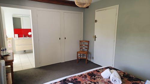 Spacious bedroom at Le Moulin de Bacchus with double bed, large closets, and doorway to kitchenette in Chancay