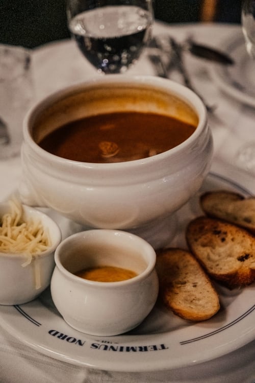 Élégant service de soupe à L'escapade Le Mans avec bols en porcelaine blanche, biscuits et verres d'eau sur table de gastronomie