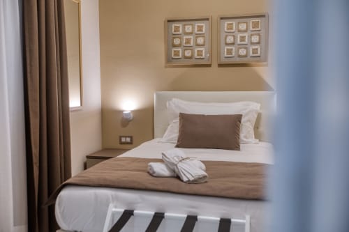 Camera elegante al Marea Sliema con biancheria bianca, cuscino marrone, arredamento moderno e vista sulla corte interna a Sliema,