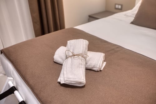 Asciugamani bianchi arrotolati legati con spago sul letto della camera d'hotel Marea a Sliema, Malta