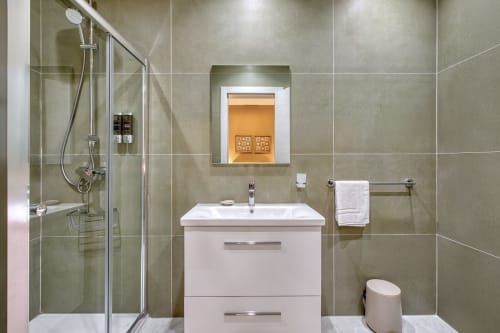 Bagno moderno a Marea Sliema con vanity bianco, doccia a cascata, scaldasalviette e piastrelle in tonalità neutre