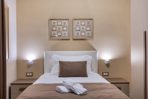 Camera moderna dell'Hotel Marea Slieme con letto queen, biancheria bianca, cuscino decorativo marrone e arte contemporanea
